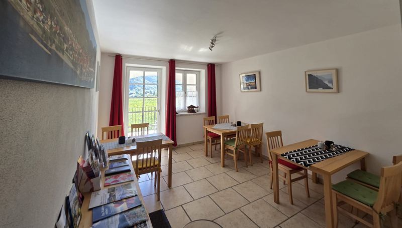 Heller Frühstücksraum mit Holztischen und Blick in die Weingärten