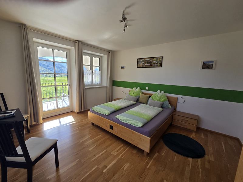 Zimmer Veltliner mit Doppelbett, Schreibtisch und Fenstertür zum Balkon