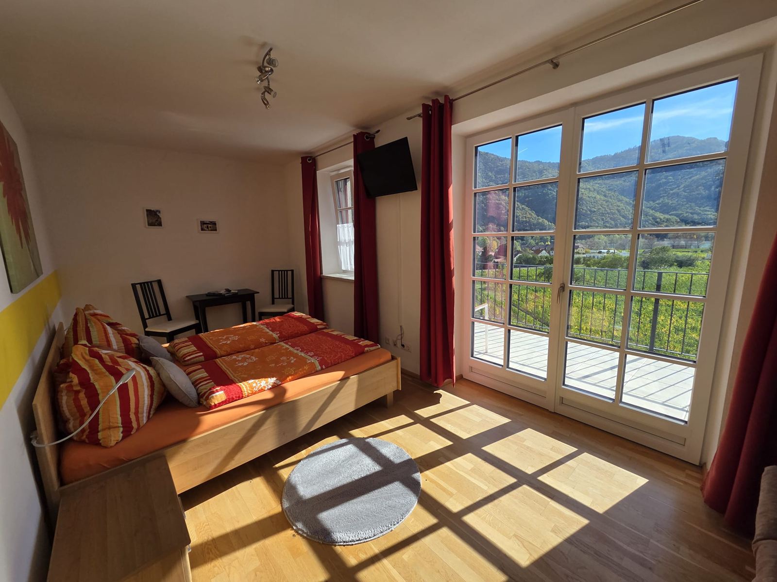 Sonniges Gästezimmer mit Doppelbett und großer Fenstertür zur Terrasse